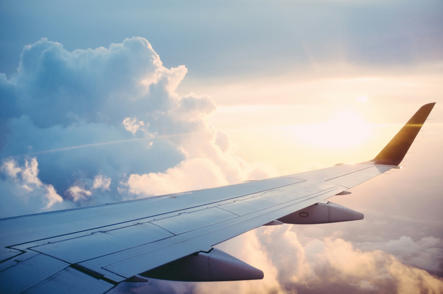 Airplane wing above the clouds at golden hour