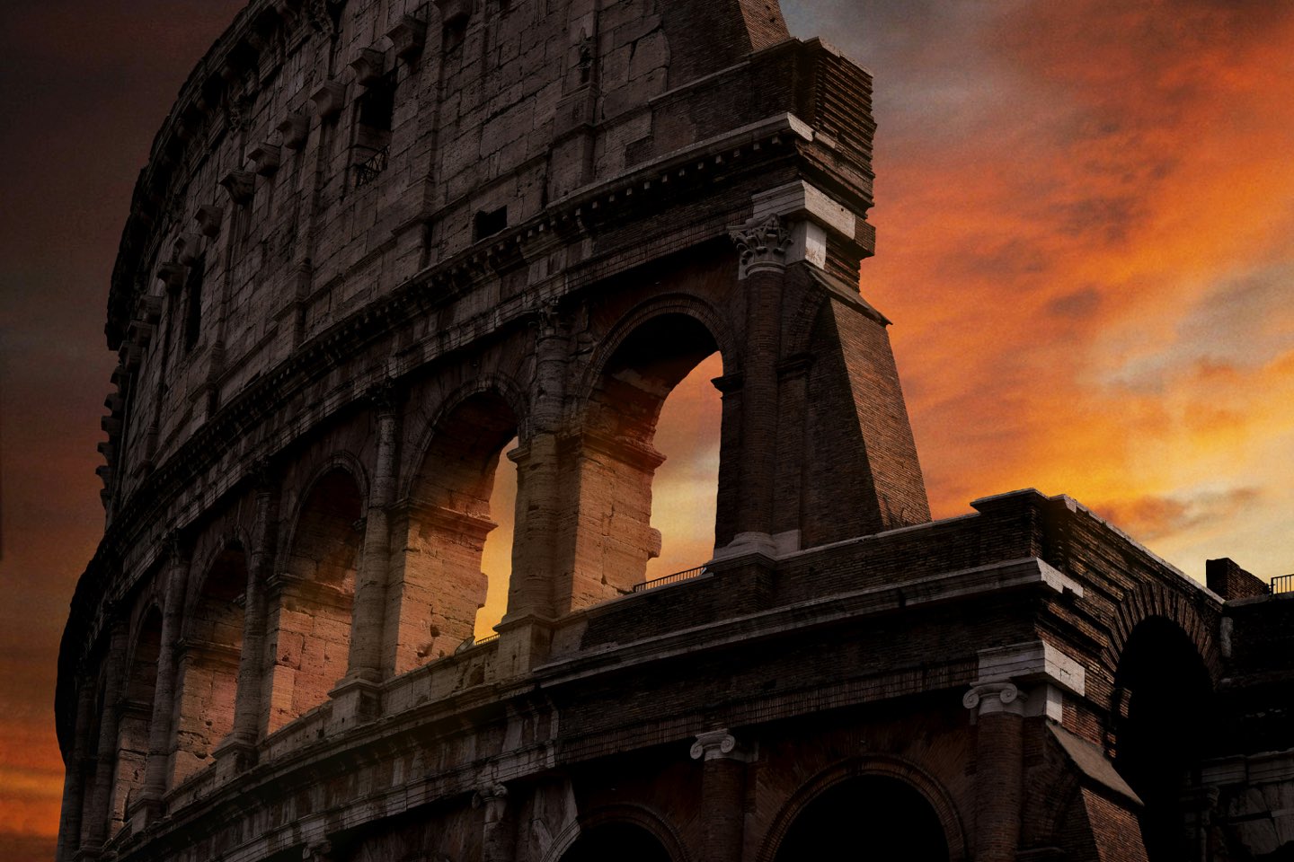 The Colosseum in Rome silhouetted against a fiery sunset sky