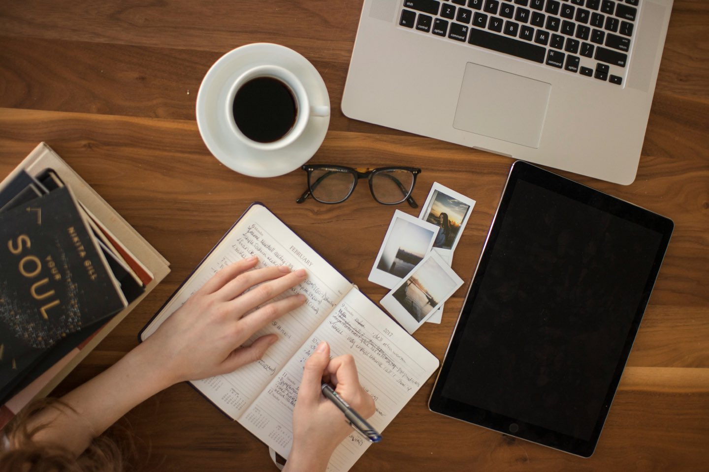 Planning a trip — journal, travel photos, coffee and laptop on a desk