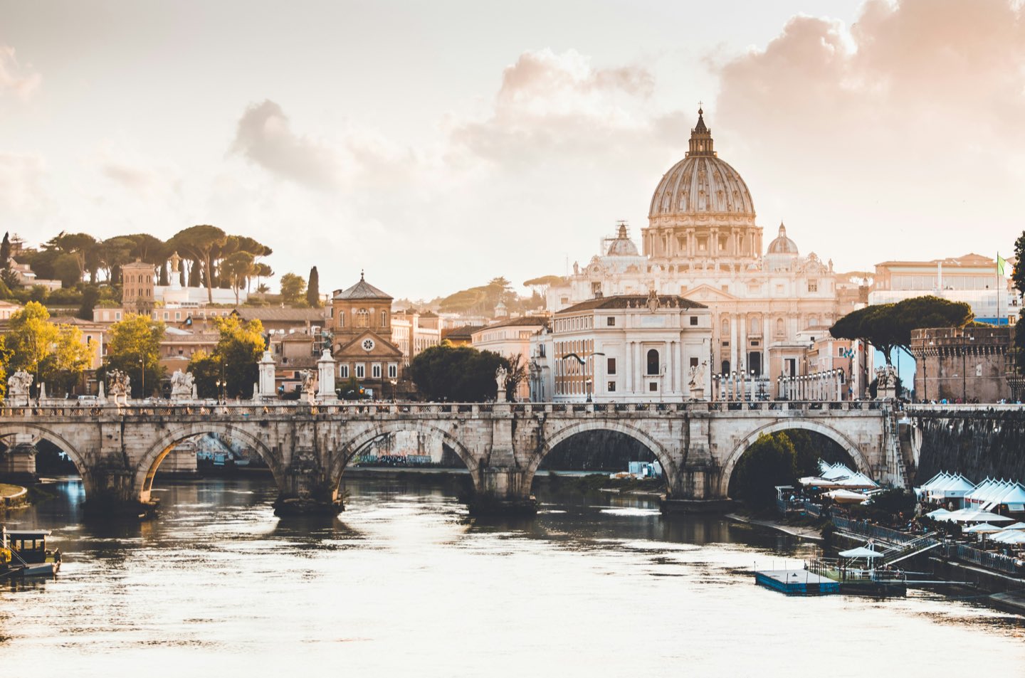 Ponte Sant'Angelo bridge and St. Peter's Basilica over the Tiber River in Rome at golden hour
