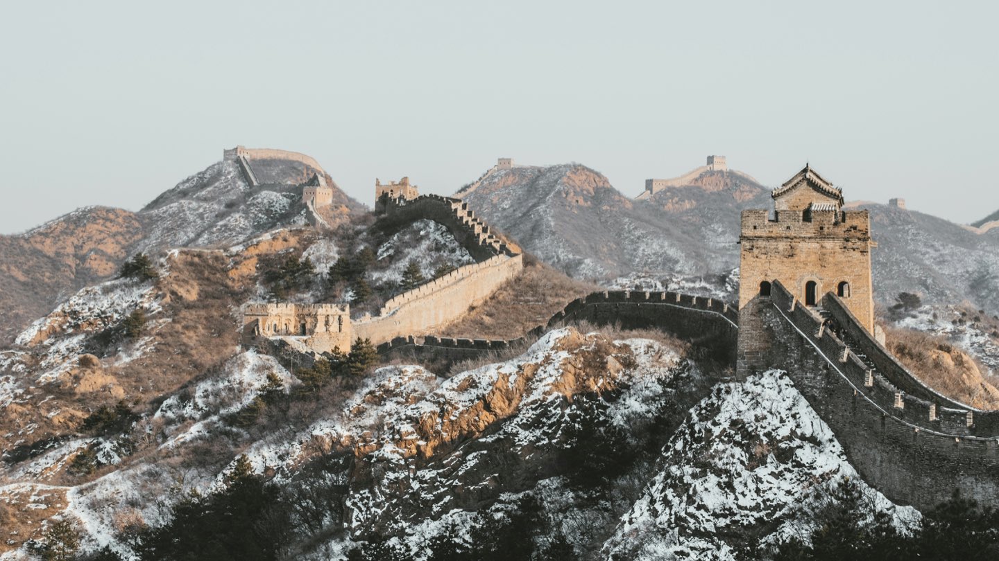 The Great Wall of China winding over snow-dusted mountain ridges at dawn