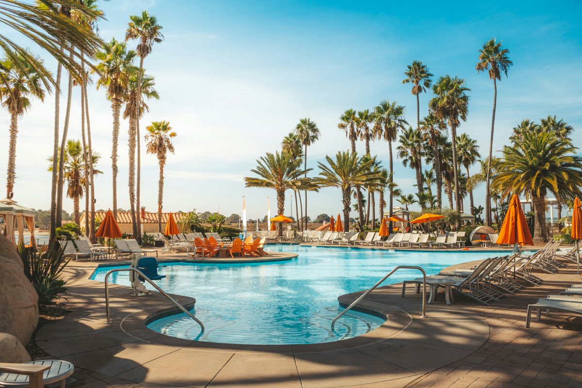 Luxury resort pool with palm trees and orange umbrellas