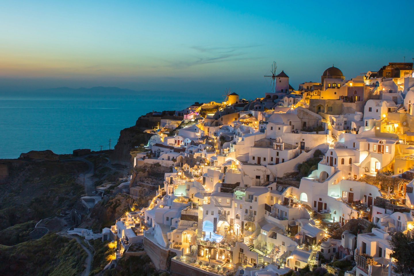 Whitewashed village of Oia glowing at dusk overlooking the Aegean Sea in Santorini